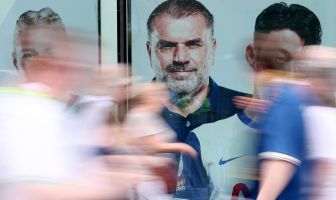 Fans of Tottenham Hotspur walk past a giant picture of Ange Postecoglou,